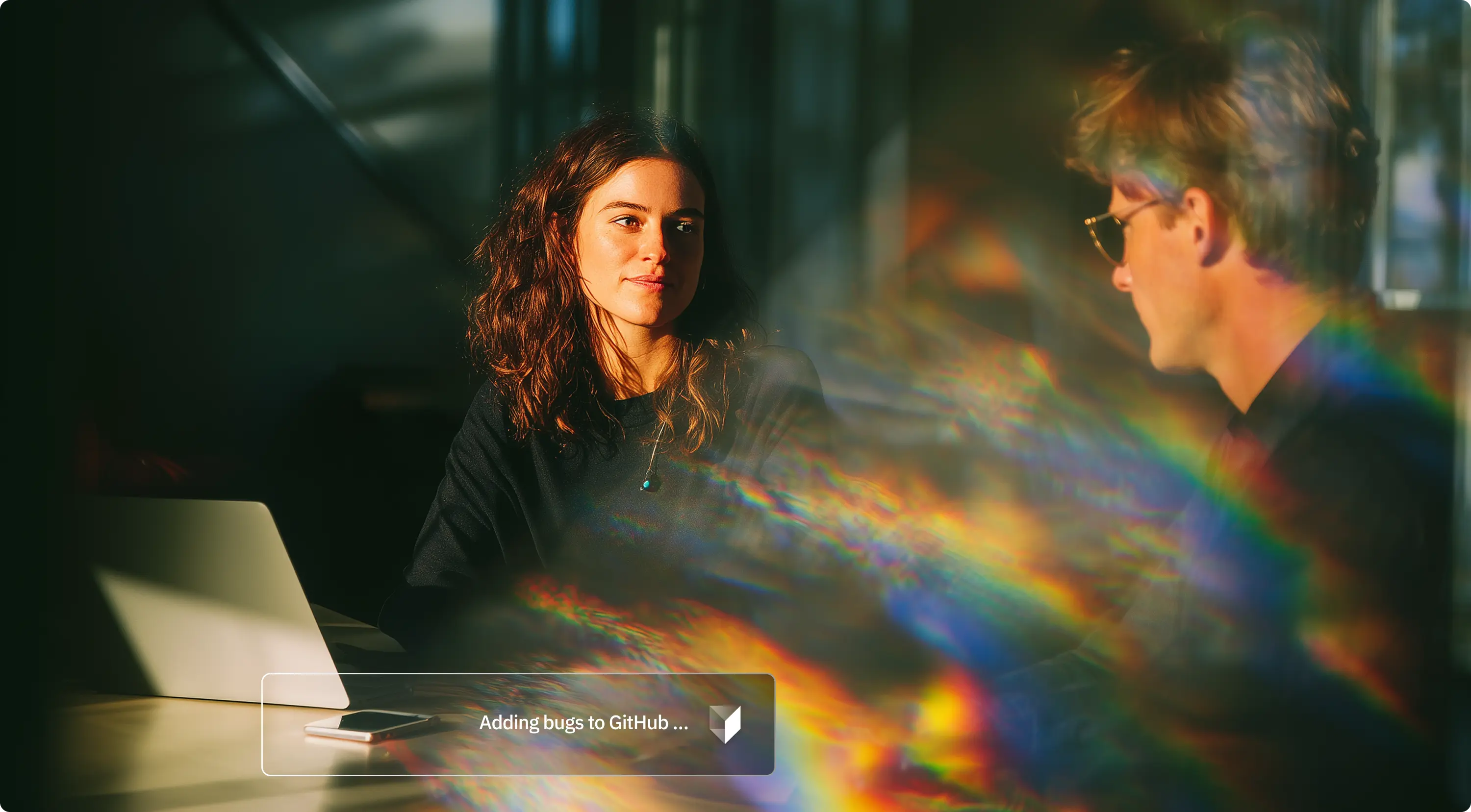 Two colleagues talking across a table in low afternoon sun